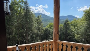 A wooden deck with a bench and railing, overlooking a forested mountain landscape. - Luxury Stowe Retreat Sleeps 18 Hot Tub & Mtn Views (Stowe)
