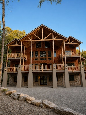 A large, multi-story lodge with a wooden exterior, multiple balconies, and a stone foundation.