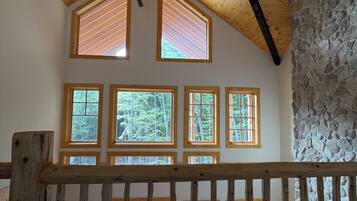 A room with a sloped ceiling, a ceiling fan, and multiple windows with wooden frames.