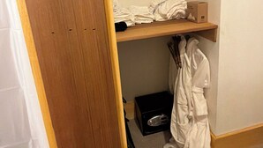A bedroom with a wooden bed frame, a white robe, and a box on the floor.