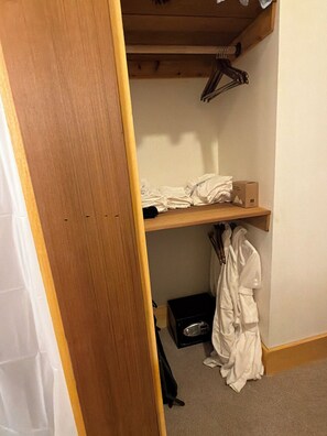 A bedroom with a wooden bed frame, a white robe, and a box on the floor.