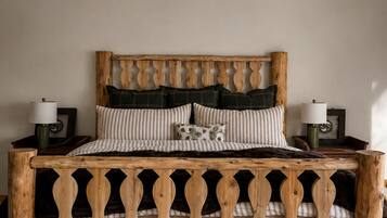 Una cama con cabecera y marco decorativos de madera. Hay dos mesitas de noche con lámparas.