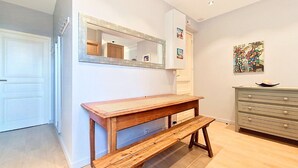 Una stanza con una panca di legno, un armadietto bianco, uno specchio e un quadro appeso al muro.