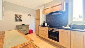 Una cucina moderna con mobili in legno, un piano cottura nero e una finestra che offre luce naturale.