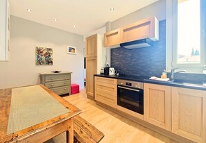 A modern kitchen with wooden cabinets, a black stove, and a window providing natural light. - New! N&J - BUFFA HARMONY - Central - Close sea (Nice)