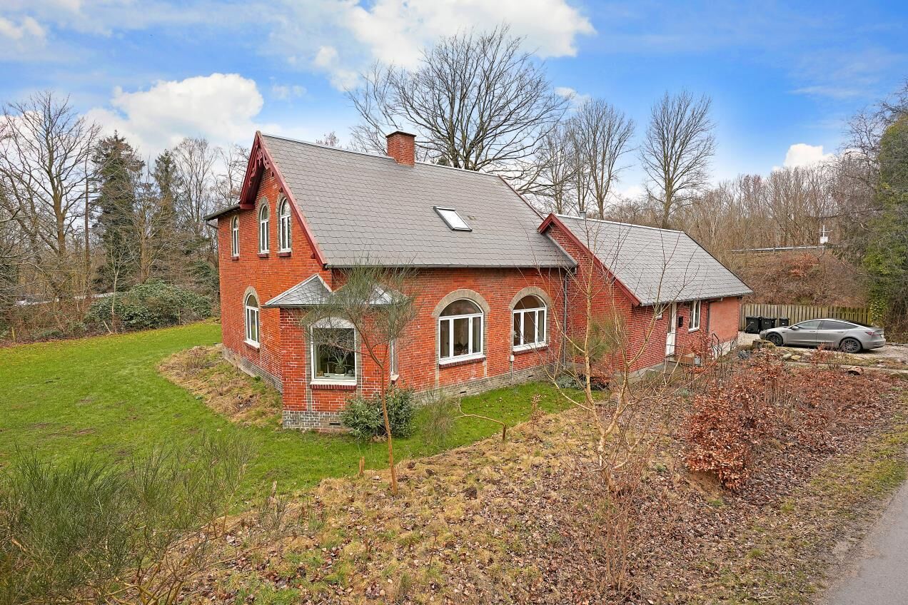 A red brick house with a sloped roof, a front porch, and a small front yard.