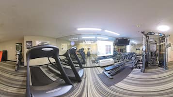 Ein Fitnessstudio mit Laufbändern, Gewichten und einer Spiegelwand.