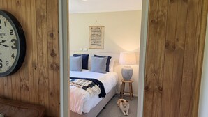 Une chambre à coucher avec un lit, des oreillers, une lampe et un chien.