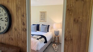 Un dormitorio con una cama, almohadas, una lámpara y un perro.