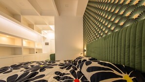 Ein modernes Schlafzimmer mit einem gemusterten Bettbezug, eingebauten Regalen und einem einzigartigen, grünen Kopfteil.