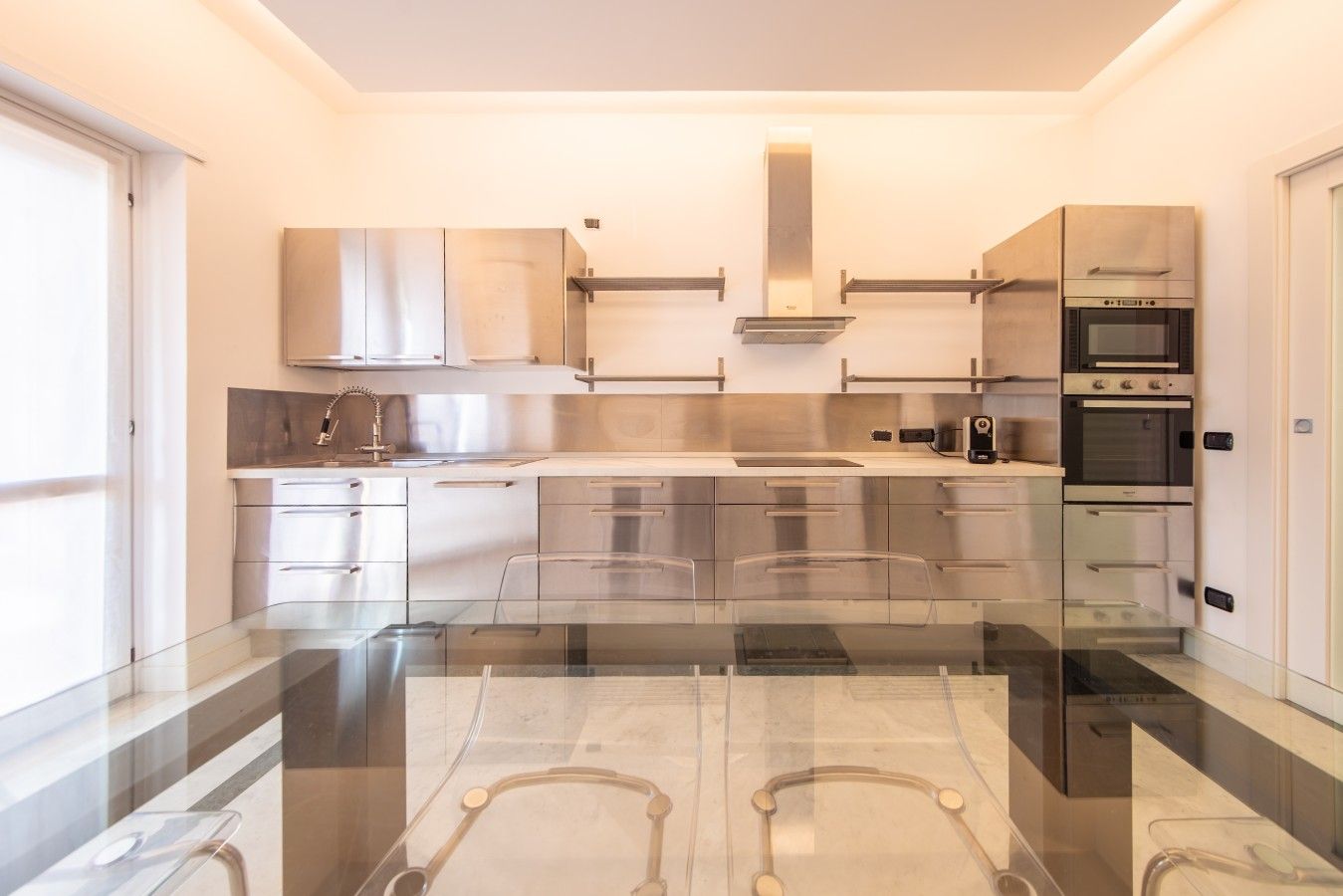 Una cocina moderna con electrodomésticos de acero inoxidable, una mesa de comedor de vidrio y vistas a la ciudad.