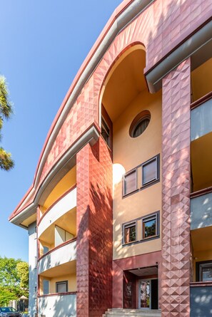A multi-story building with a curved facade, balconies, and a central entrance.