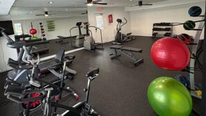 A gym with exercise equipment, a ceiling fan, and a wall-mounted fire extinguisher. - Comfortable Townhome with Modern Interiors (Indianapolis)