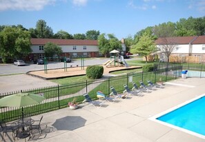 Ein Poolbereich mit Liegestühlen und einem umzäunten Spielplatz.