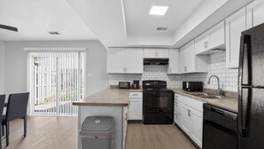 A modern kitchen with white cabinets, a black refrigerator, and a built-in oven. - Comfortable Townhome with Modern Interiors (Indianapolis)