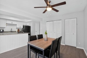 Eine moderne Küche mit weißen Schränken, einem schwarzen Kühlschrank und einem Holzespeisetisch mit Stühlen.