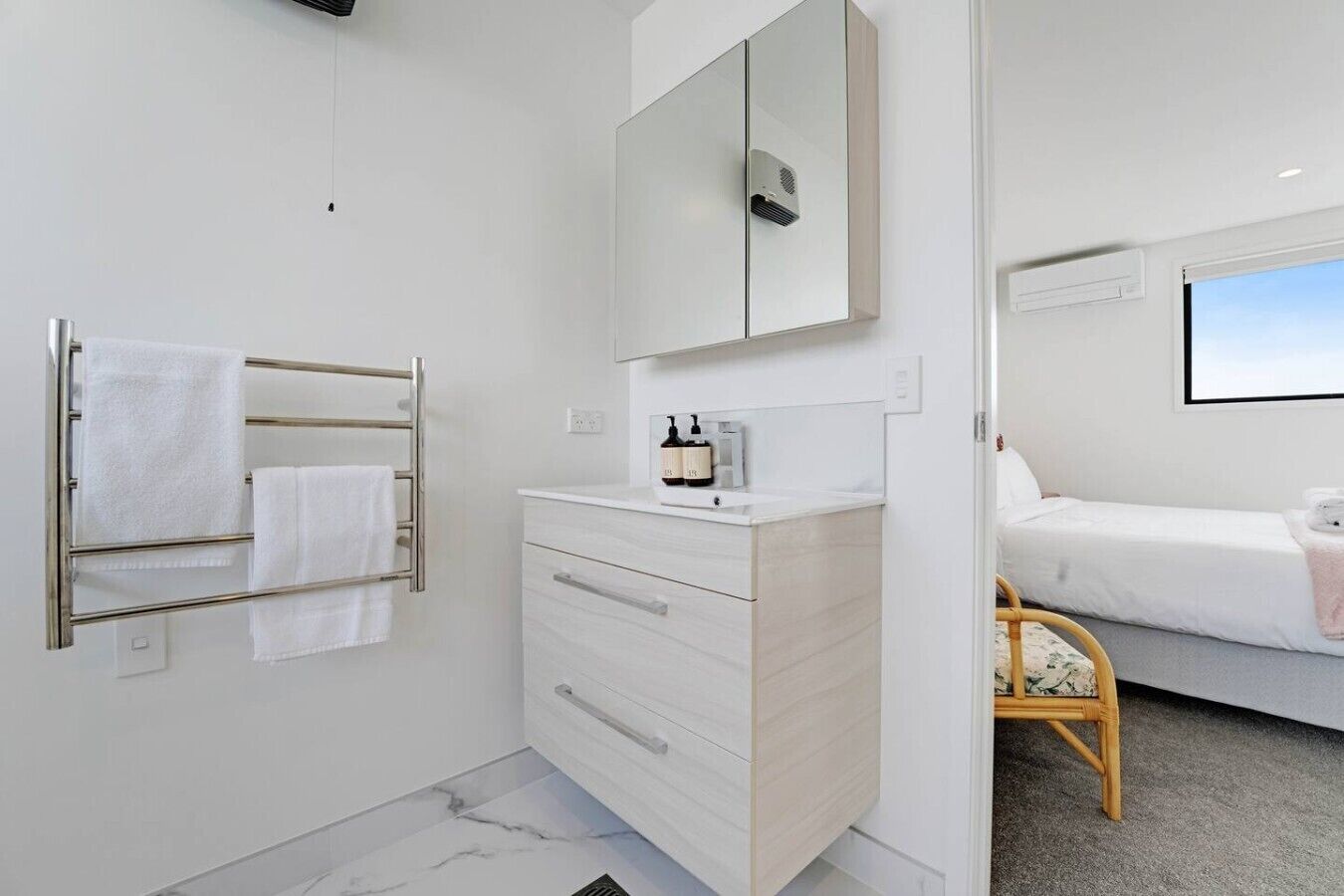 Une salle de bain moderne équipée d’un porte-serviettes, d’une commode avec des tiroirs, d’un miroir et d’un lit donnant sur un beau paysage.