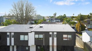 A residential building with a flat roof, multiple windows, and a visible garage.