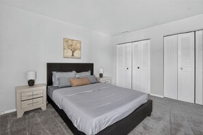 A bedroom with a bed, nightstands, a lamp, a painting, and a wardrobe. - Spacious Townhome Designed for Relaxing Stays (Indianapolis)
