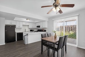 A modern kitchen with white cabinets, a black refrigerator, and a dining area with a wooden table and chairs. - Spacious Townhome Designed for Relaxing Stays (Indianapolis)