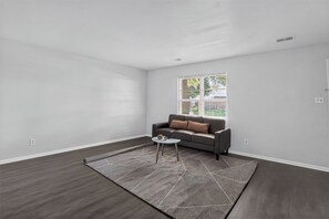 A modern living room with a grey sofa, a small round table, and a patterned rug. - Spacious Townhome Designed for Relaxing Stays (Indianapolis)