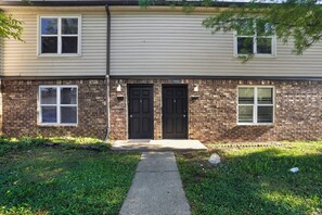 A two-story building with a brick facade, two black doors, and a small front yard with a concrete path leading to the entrance. - Spacious Townhome Designed for Relaxing Stays (Indianapolis)