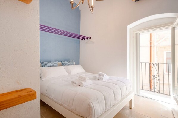 A bedroom with a bed, pillows, a hanging towel rack, and a view of the outside.