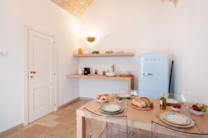 A modern kitchen with a dining table set for two, a built-in oven, and a refrigerator.