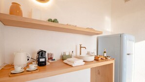 Una kitchenette moderna con cafetera, hervidor y tetera sobre la encimera.