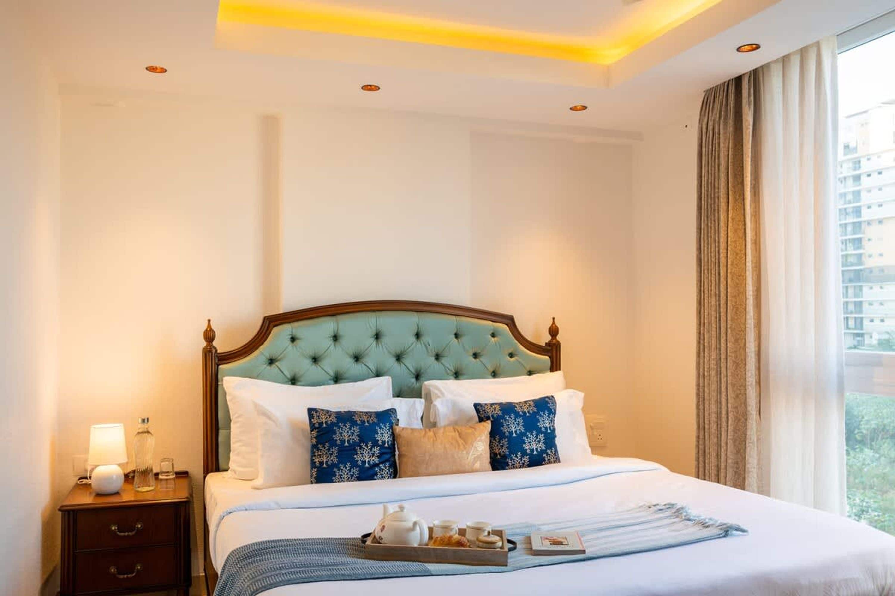 A hotel room with a large bed, a nightstand, a lamp, and a window with curtains.