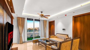 Une chambre d’hôtel avec un grand lit, un canapé, une télévision et un ventilateur de plafond.