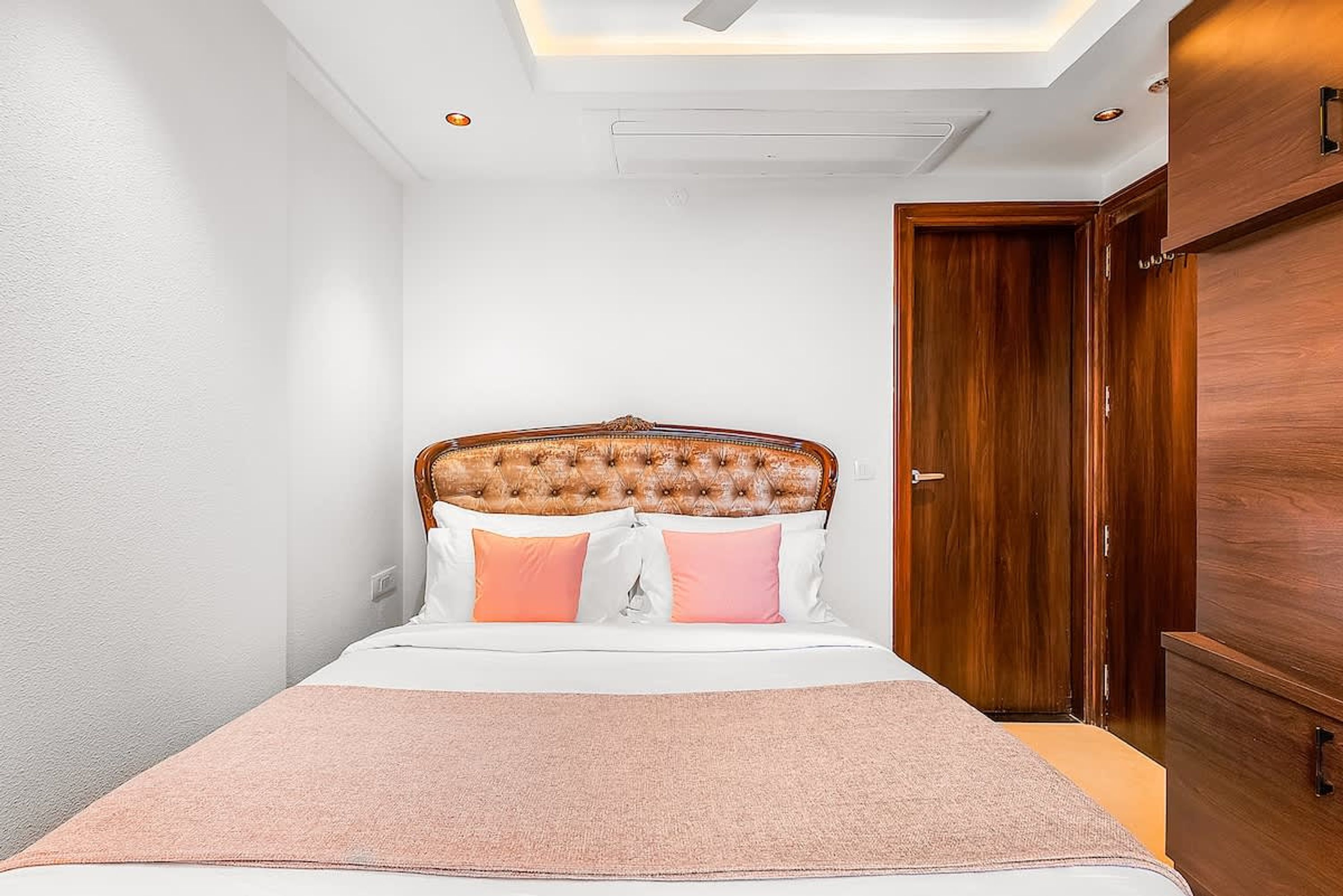 Un dormitorio con cama, armario de madera y lámpara en el techo.