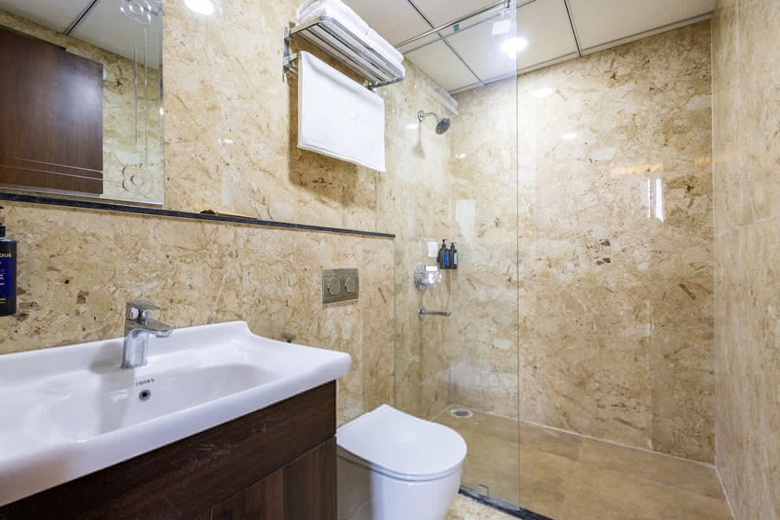 A bathroom with a marble sink, a mirror, a towel rack, and a shower.