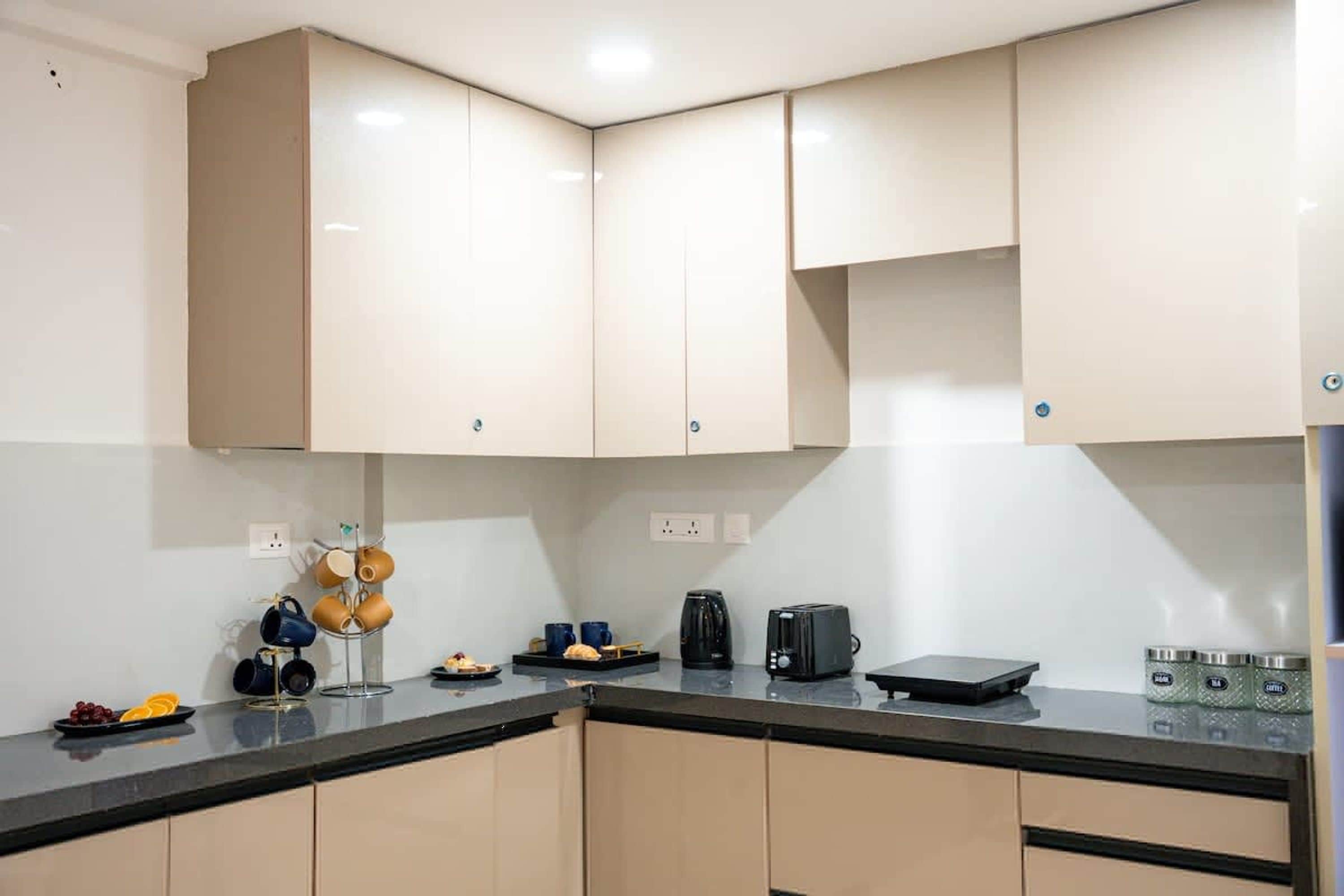 Una cocina con armarios color beige, encimera negra y una cafetera.