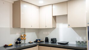 Une cuisine avec des meubles de couleur beige, un plan de travail noir et une machine à café.