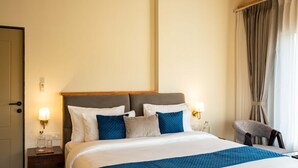 Ein Hotelzimmer mit Bett, Nachttischen, einem Sessel und Vorhängen.