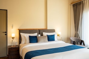 A hotel room with a bed, bedside tables, a chair, and curtains.