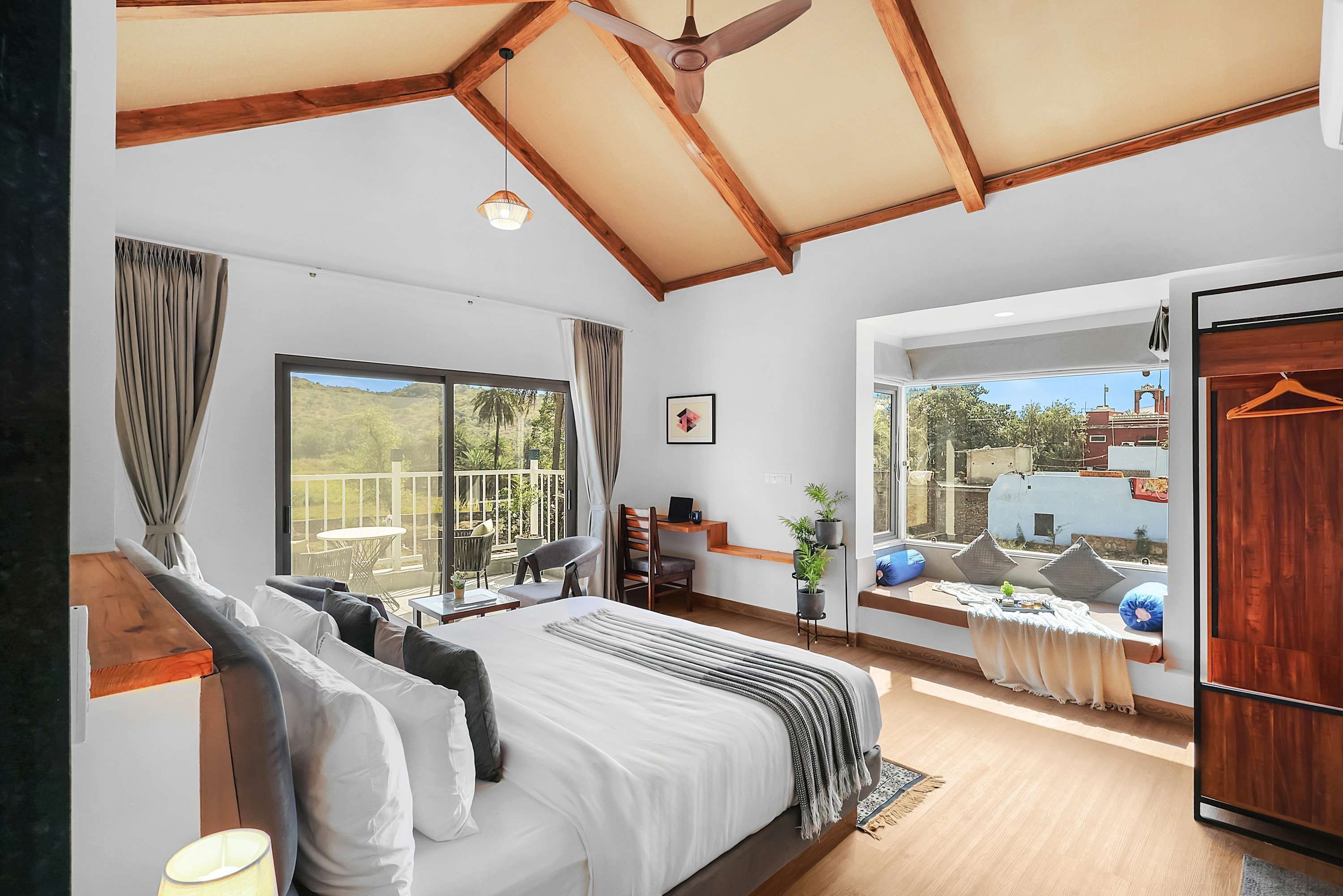 A bedroom with a large bed, a ceiling fan, and a view of the outdoors.