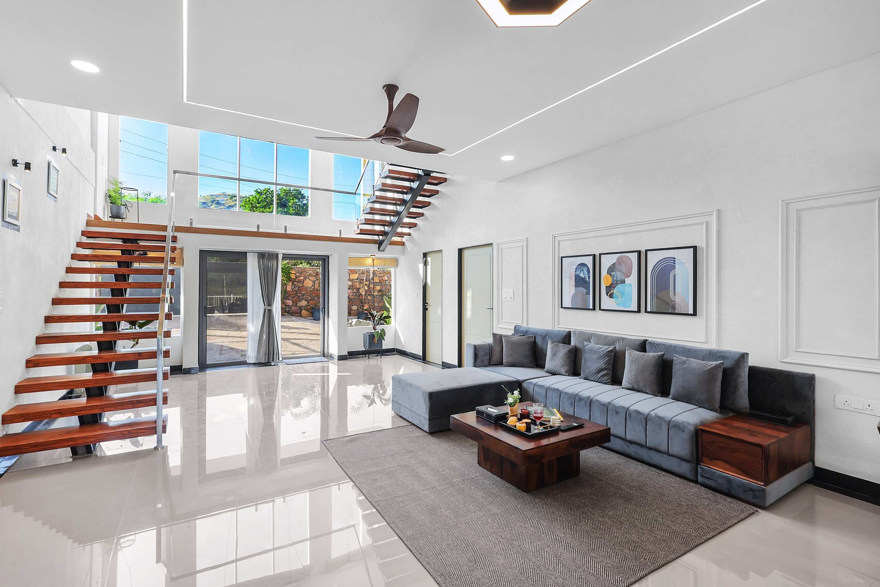 A spacious living area with a modern staircase, a sectional sofa, and a coffee table.