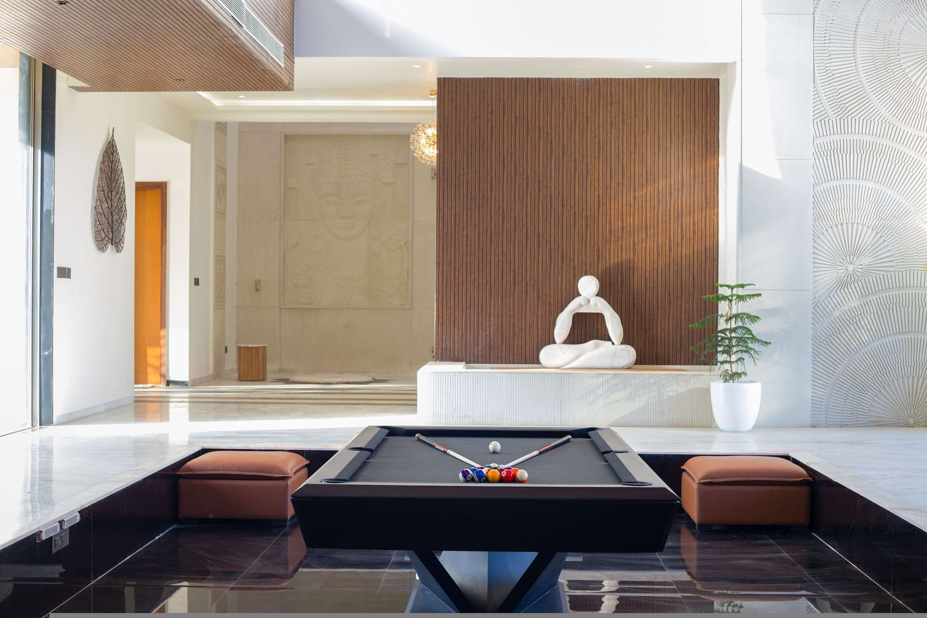A modern indoor pool table with a pool cue, balls, and two cushioned seating areas.