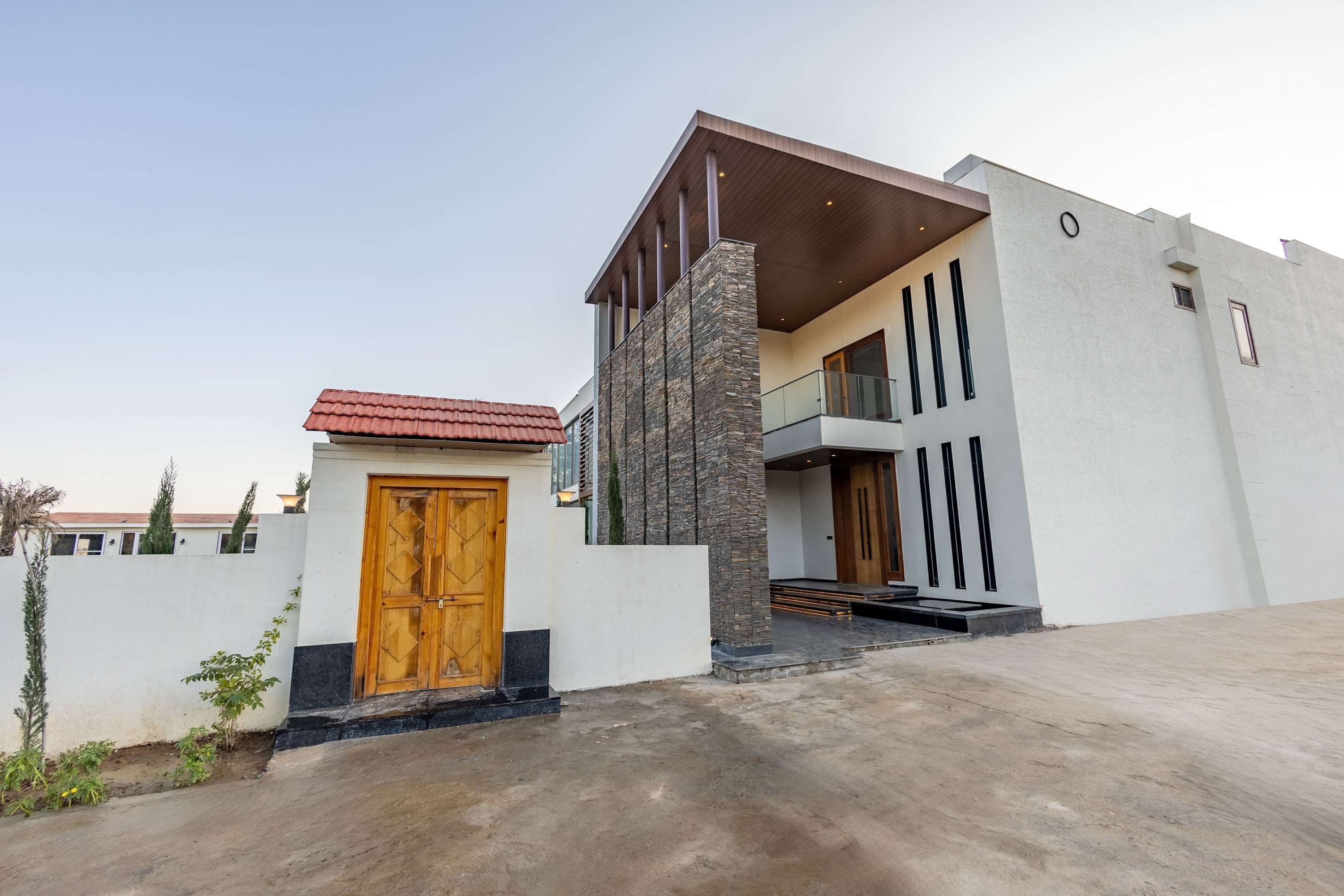 A modern two-story building with a prominent wooden door and a stone facade.