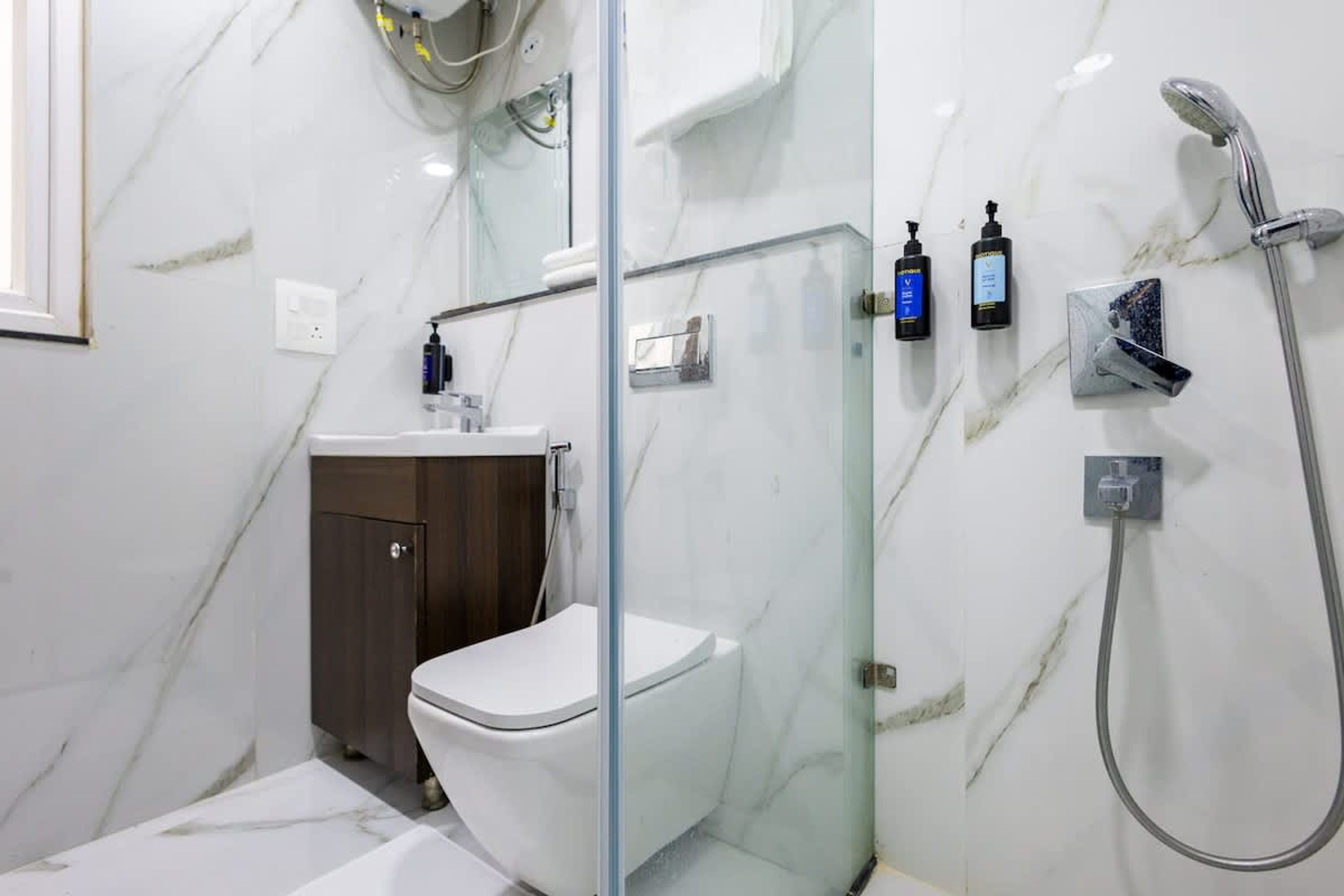 Un baño moderno con ducha de vidrio, inodoro blanco y mueble de madera.