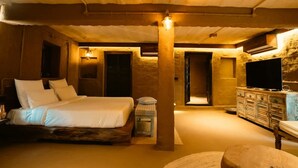A bedroom with a bed, a television, and a wooden cabinet.