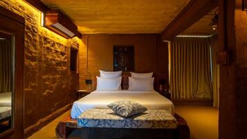 Un dormitorio con cama, mesita de noche, espejo y ventana con cortinas.