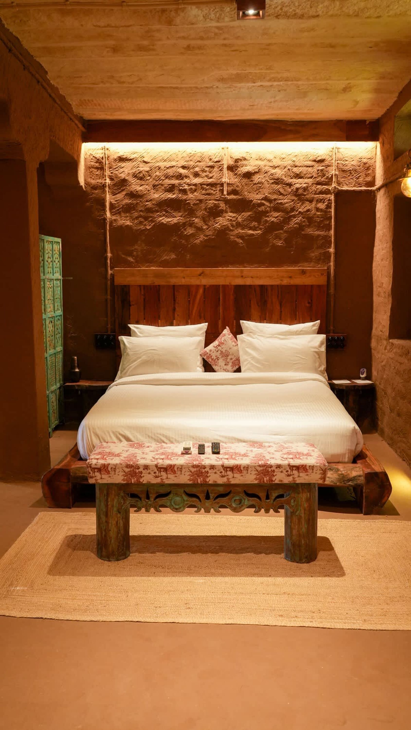A large bed with a wooden headboard and a hanging light fixture above it.
