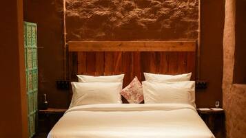 A large bed with a wooden headboard and a hanging light fixture above it.