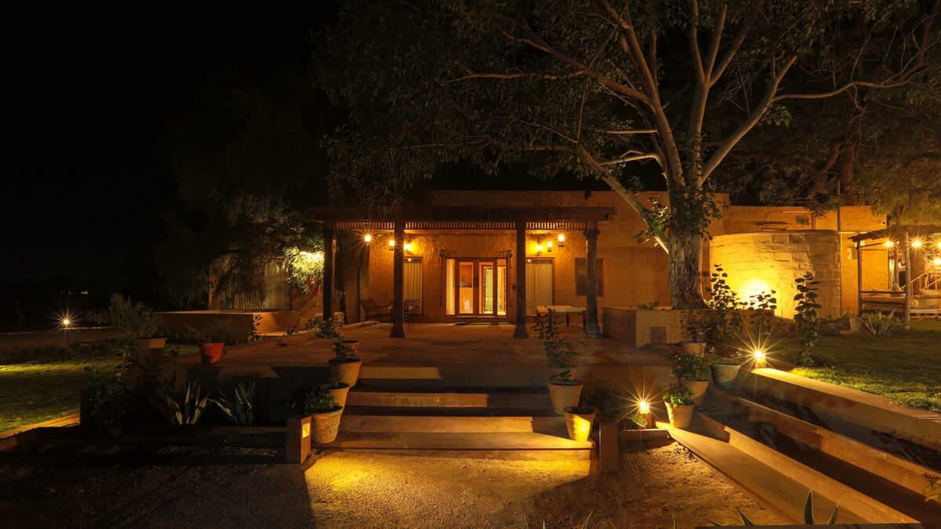 A building with a covered entrance, outdoor seating, and potted plants.