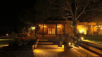 A building with a covered entrance, outdoor seating, and potted plants.