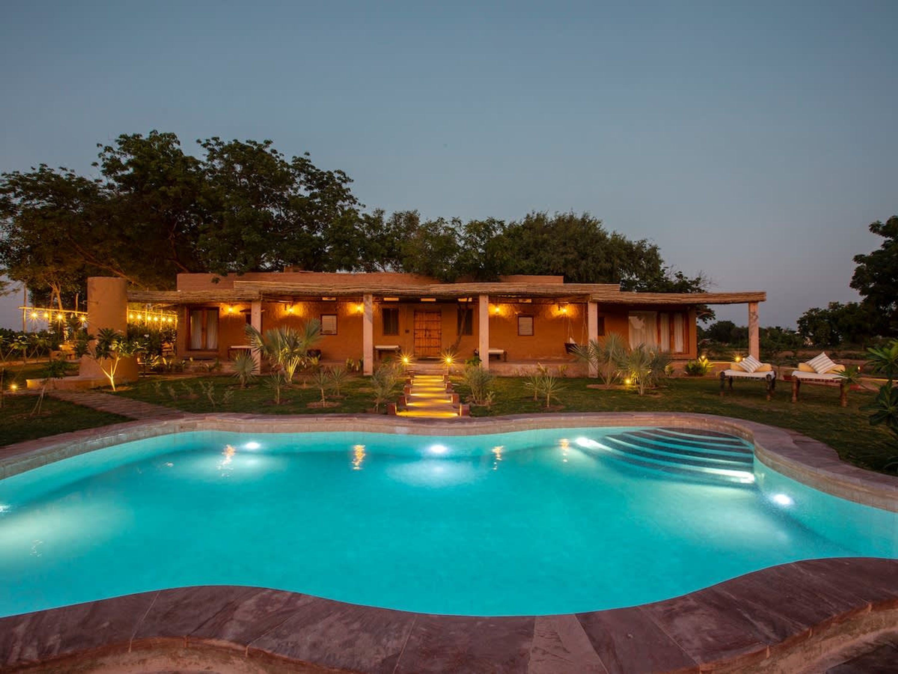 Una casa con piscina, porche cubierto e iluminación exterior.