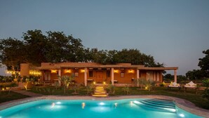 Una casa con piscina, portico coperto e illuminazione esterna.